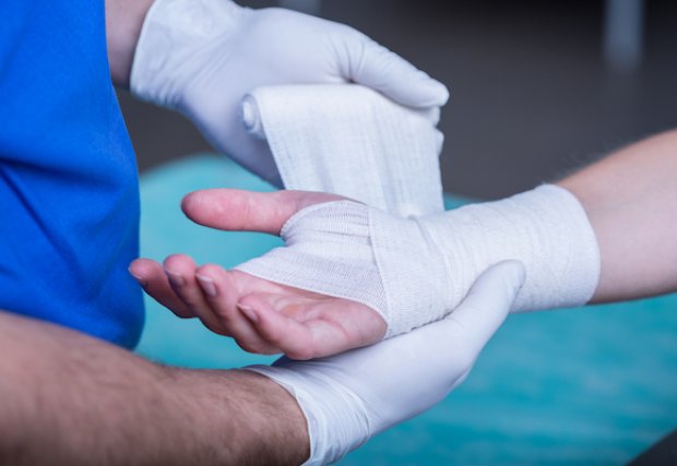 A doctor wrapping a wound on a patient's arm